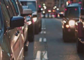 Foto tirada no meio da rua, mostrando diversos veículos em um trânsito parado.