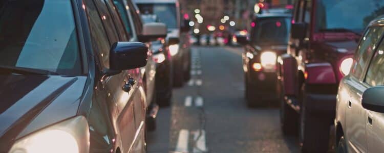 Foto tirada no meio da rua, mostrando diversos veículos em um trânsito parado.