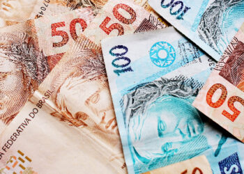 Várias notas de 100 reais e 50 reais espalhadas.