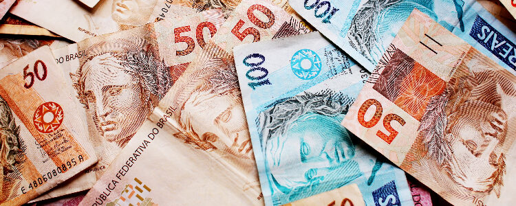 Várias notas de 100 reais e 50 reais espalhadas.