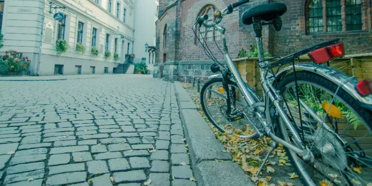 O chão de uma rua na Europa com uma bicicleta encostada na parede.