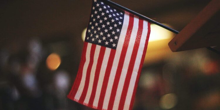 Bandeira dos Estados Unidos em um mastro. O fundo está desfocado e está de noite.