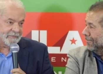 O presidente Luiz Inácio Lula da Silva segurando um microfone e conversando com o ministro Carlos Lupi.