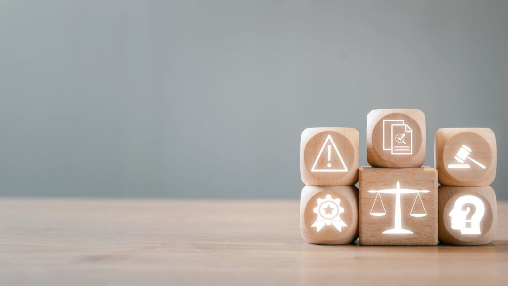 Blocos de madeira com ícones que simbolizam conceitos de regulamentação, conformidade e governança