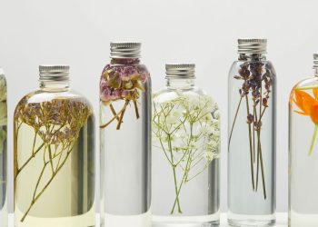 Garrafas de vidro cheias de líquido transparente com flores dentro - Créditos: depositphotos.com / AntonMatyukha