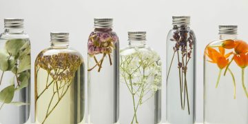 Garrafas de vidro cheias de líquido transparente com flores dentro - Créditos: depositphotos.com / AntonMatyukha