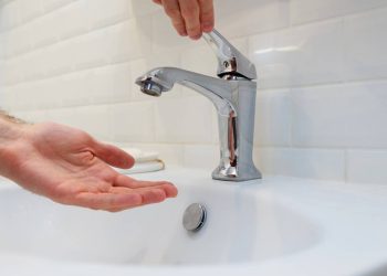 Homem segurando a mão debaixo de uma torneira aberta sem água - Créditos: depositphotos.com / vladeephoto.gmail.com