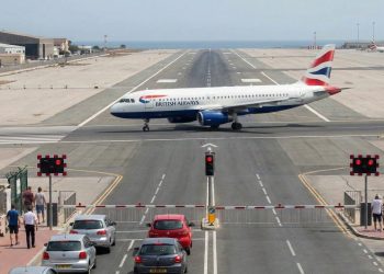 A avenida que cruza a pista de um aeroporto internacional e obriga carros a pararem no sinal vermelho para um avião decolar