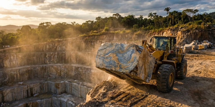 Uma pá carregadeira move um bloco gigante de rocha exótica em uma pedreira ao pôr do sol no Espírito Santo.