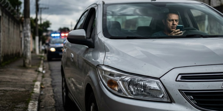 Motorista apreensivo em carro de 2016 com luzes de blitz ao fundo
