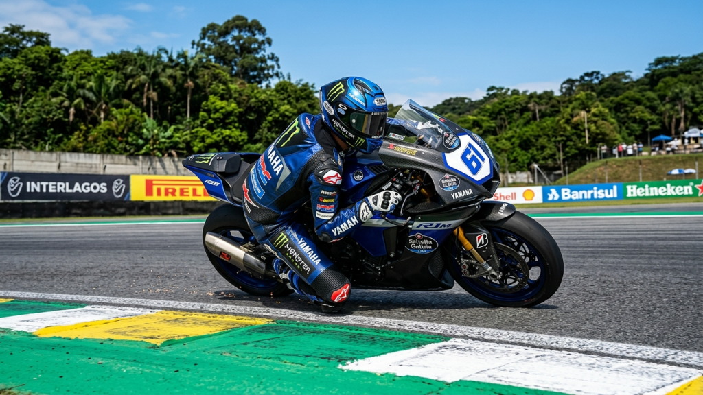 Piloto inclinando a motocicleta em uma curva fechada de um autódromo.