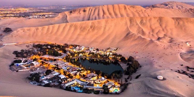 Com dezenas de palmeiras e dunas gigantes, o oásis de Huacachina surge como uma miragem surreal escondida no meio do deserto peruano