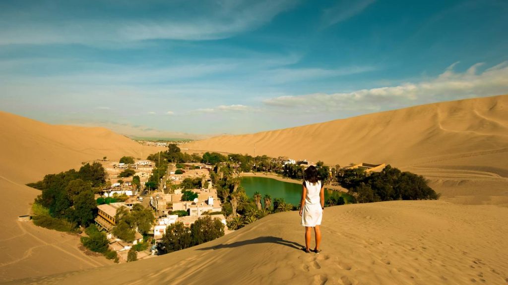Com dezenas de palmeiras e dunas gigantes, o oásis de Huacachina surge como uma miragem surreal escondida no meio do deserto peruano