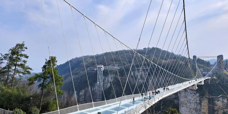 Suspensa a 300 metros de altura com 99 painéis de vidro na passarela principal, a estrutura de 430 metros de extensão desafia a coragem de pedestres na China