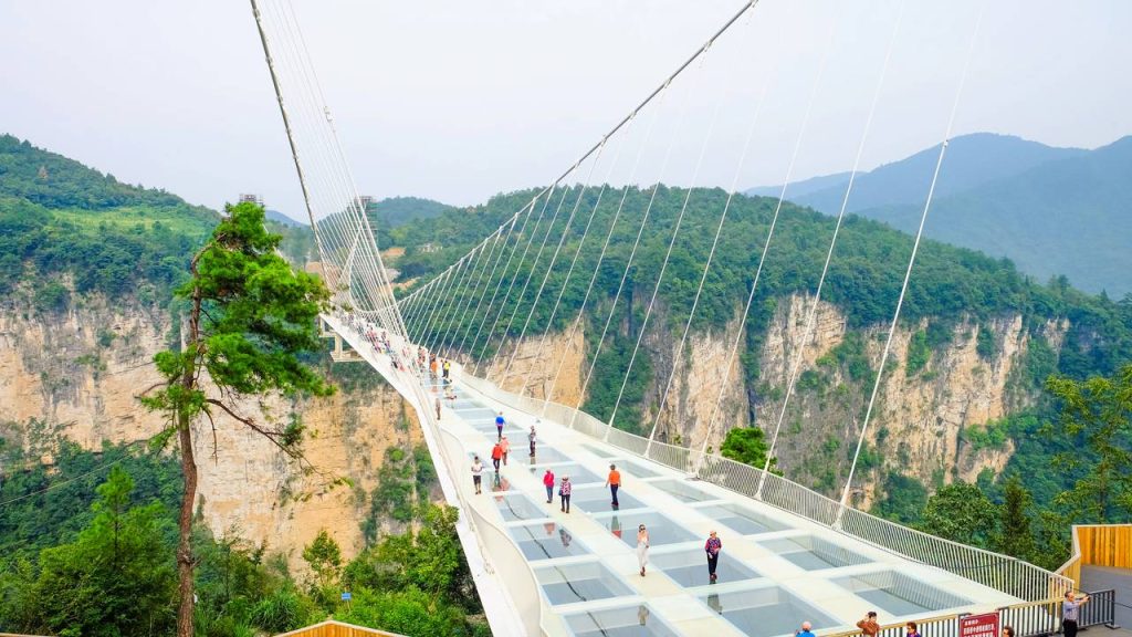 Suspensa a 300 metros de altura com 99 painéis de vidro na passarela principal, a estrutura de 430 metros de extensão desafia a coragem de pedestres na China