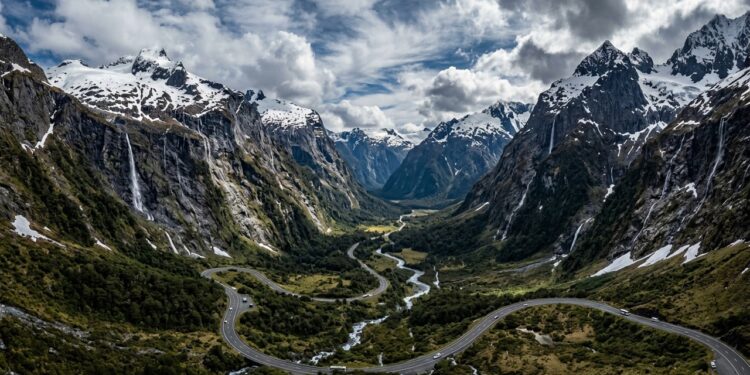 Com túneis escavados na rocha sólida e paredões com cachoeiras, a estrada desce as montanhas neozelandesas até o espetacular fiorde de Milford