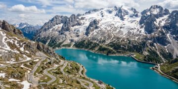 Com rampas íngremes de até dezoito por cento de inclinação nas Dolomitas, a estrada histórica margeia um lago glacial no topo da montanha italiana