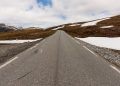A rodovia na Noruega estende-se por 47 km de asfalto sinuoso; subindo a 1.306 metros de altitude, a rota revela corredores de neve no verão