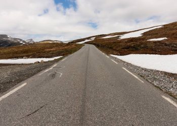 A rodovia na Noruega estende-se por 47 km de asfalto sinuoso; subindo a 1.306 metros de altitude, a rota revela corredores de neve no verão
