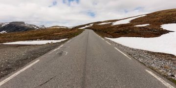 A rodovia na Noruega estende-se por 47 km de asfalto sinuoso; subindo a 1.306 metros de altitude, a rota revela corredores de neve no verão