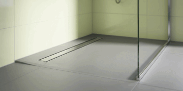 Este corte milimétrico no canto do box parece apenas detalhe estético de hotel, mas resolve o escoamento do chuveiro de alta vazão sem precisar cortar o piso em quatro águas