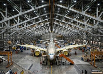 Um gigantesco hangar abriga aviões tão longos quanto prédios altos sob treliças que vencem 91 metros sem pilares centrais