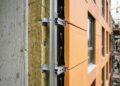 A parede não encosta diretamente no prédio: uma segunda pele fica alguns centímetros afastada da fachada e cria um corredor de ar escondido do lado de fora