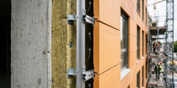 A parede não encosta diretamente no prédio: uma segunda pele fica alguns centímetros afastada da fachada e cria um corredor de ar escondido do lado de fora