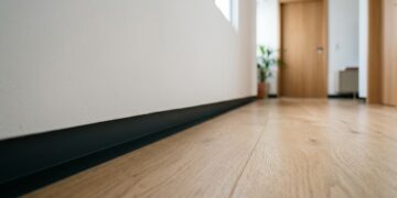 Sem rodapé aparecendo na parede, um recuo de poucos centímetros cria uma linha de sombra junto ao chão e muda completamente o acabamento dos ambientes