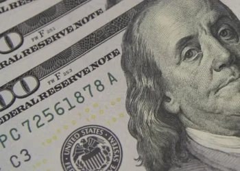 Painel eletrônico exibindo cotação do dólar em ambiente de bolsa de valores.